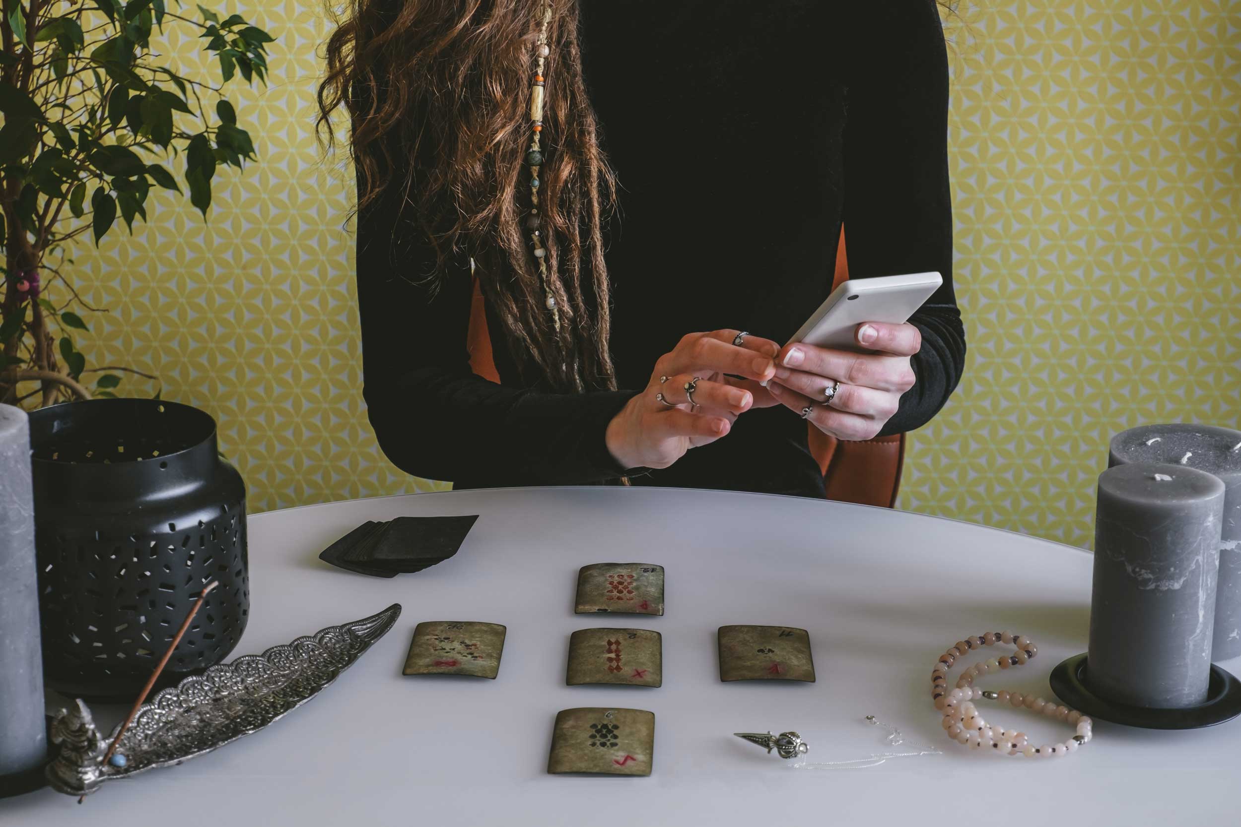 Woman holding a phone and reading tarot cards